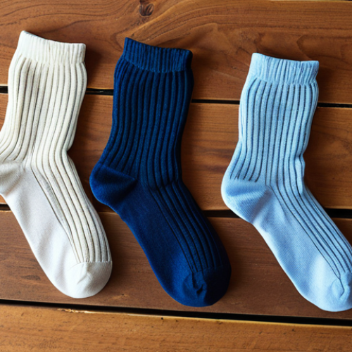 Home 15 **
A close-up photo of three different types of socks (cotton, synthetic, Merino wool) laid out side-by-side. Each sock should have a label clearly indicating its material. The background should be simple, perhaps a wooden surface, to focus attention on the socks. The lighting should be bright and even to show the texture of each material. The scene should visually communicate the differences in texture and appearance between the sock types.
**